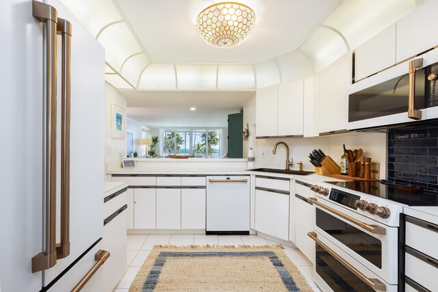 kitchen with white cabinetry, sink, backsplash, light tile patterned floors, and white appliances