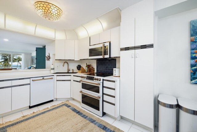 kitchen featuring sink, tasteful backsplash, light tile patterned floors, white appliances, and white cabinets