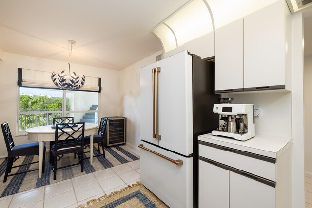 kitchen featuring pendant lighting, white cabinetry, white refrigerator, a notable chandelier, and light tile patterned flooring