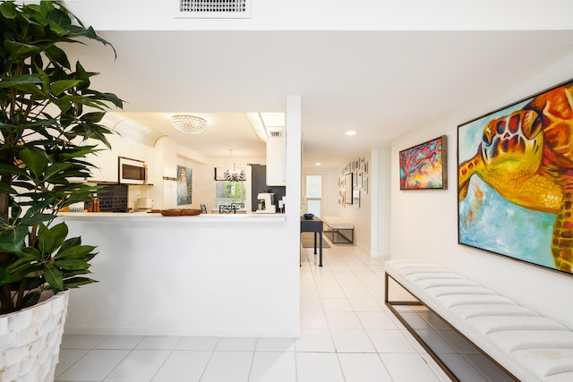 kitchen featuring light tile patterned flooring, stainless steel refrigerator, kitchen peninsula, and white cabinets