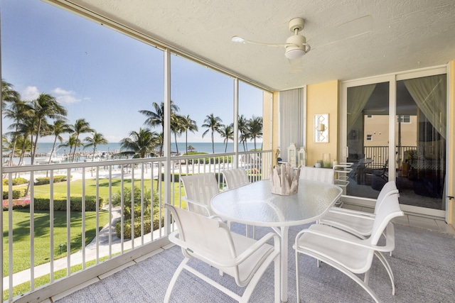 sunroom / solarium with a water view and ceiling fan