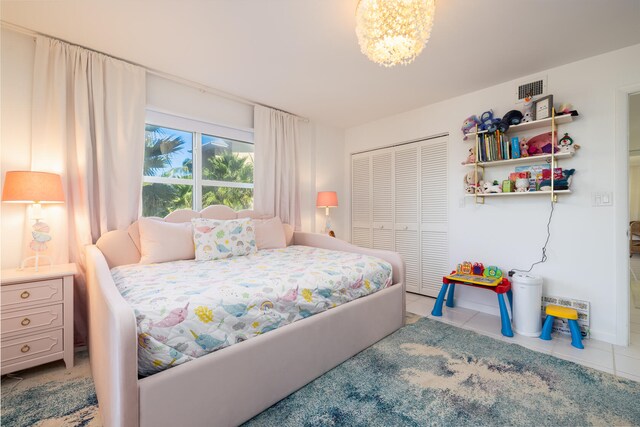 bedroom featuring tile patterned flooring, an inviting chandelier, and a closet