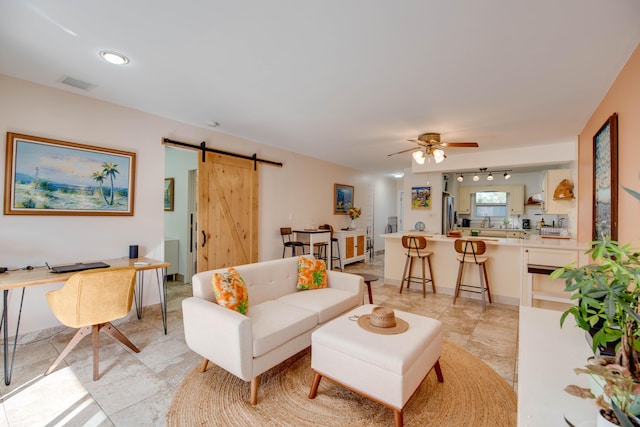 living room with ceiling fan and a barn door