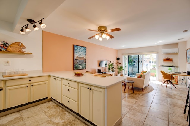 kitchen featuring ceiling fan, kitchen peninsula, cream cabinets, and an AC wall unit