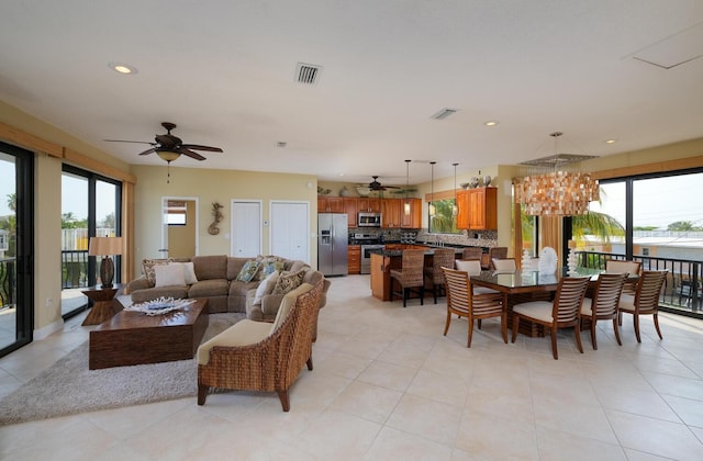 tiled living room with ceiling fan with notable chandelier and plenty of natural light