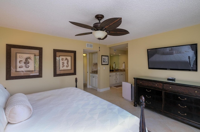 bedroom featuring ceiling fan, ensuite bathroom, a textured ceiling, and light tile patterned floors