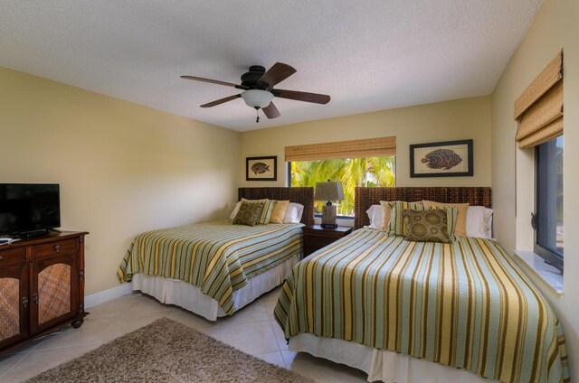 bedroom featuring ceiling fan, light tile patterned floors, and a textured ceiling