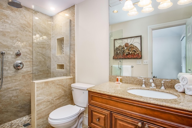 bathroom with tiled shower, vanity, and toilet