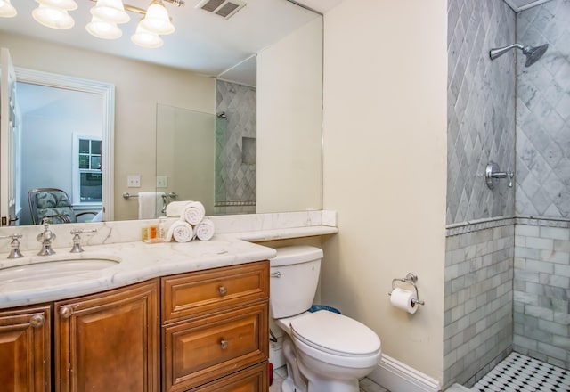 bathroom with vanity, toilet, and a tile shower