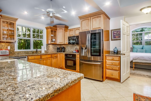 kitchen with light stone countertops, light tile patterned floors, decorative backsplash, and black appliances