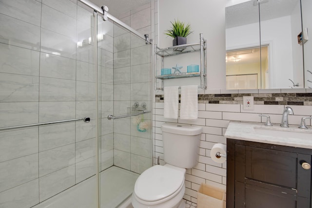 bathroom featuring vanity, a shower with door, tile walls, and toilet