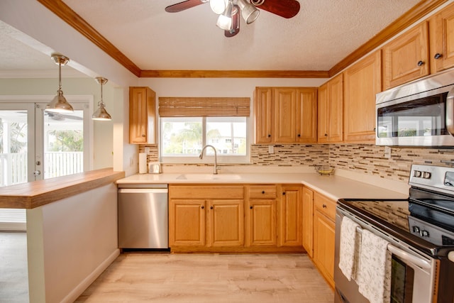 kitchen featuring pendant lighting, sink, crown molding, appliances with stainless steel finishes, and kitchen peninsula