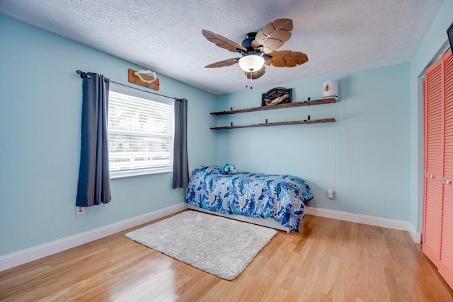 bedroom featuring ceiling fan, light hardwood / wood-style floors, a closet, and a textured ceiling