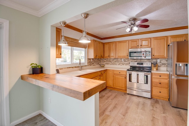 kitchen with wooden counters, light hardwood / wood-style flooring, ornamental molding, kitchen peninsula, and stainless steel appliances