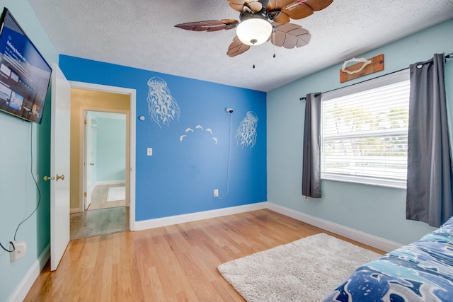 bedroom with ceiling fan, hardwood / wood-style floors, and a textured ceiling