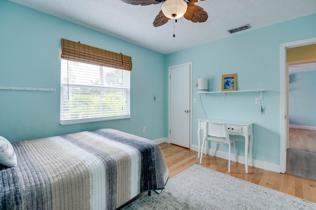 bedroom with ceiling fan, a textured ceiling, and light wood-type flooring