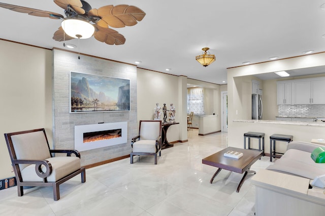 living room with crown molding, ceiling fan, and a tiled fireplace