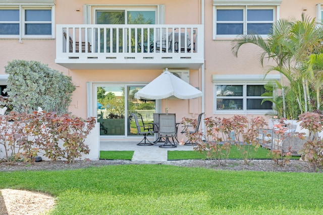 rear view of house featuring a balcony, a patio, and a lawn