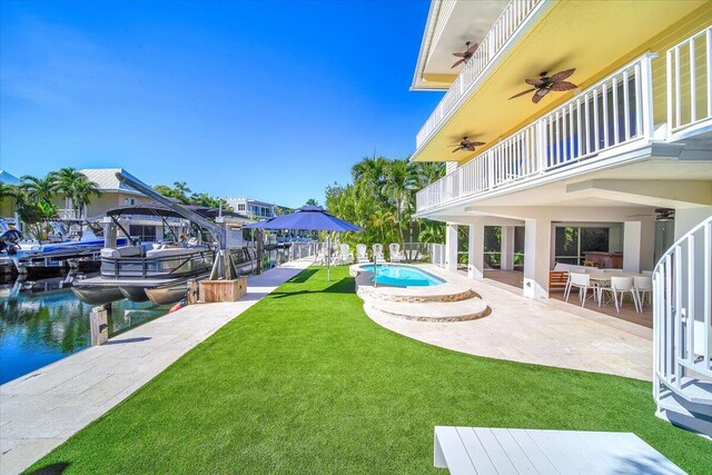 view of yard featuring a fenced in pool, ceiling fan, a patio, a water view, and a balcony