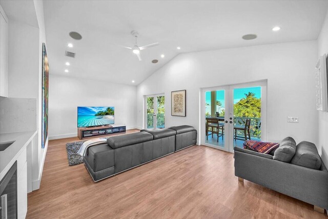 living room with lofted ceiling, light hardwood / wood-style flooring, ceiling fan, french doors, and beverage cooler