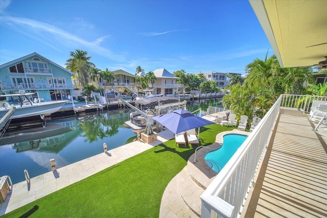 view of swimming pool with a patio, a water view, a dock, and a lawn