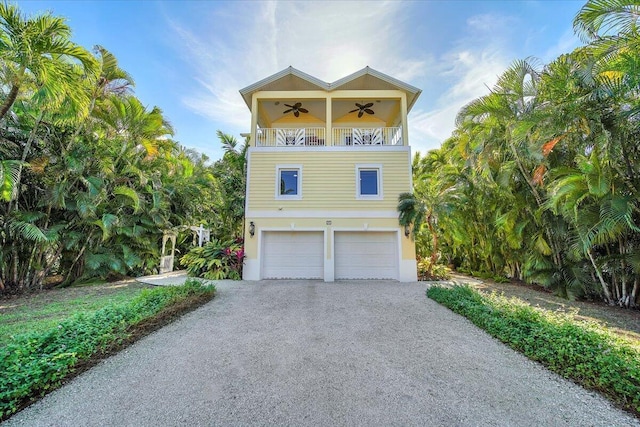 raised beach house featuring a garage, a balcony, and ceiling fan