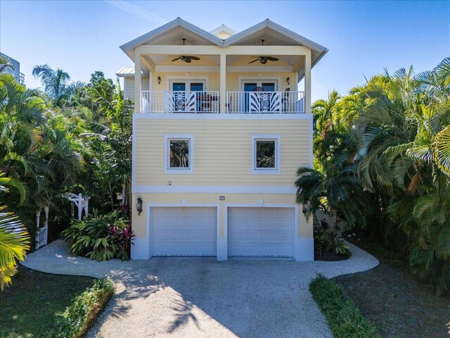 raised beach house featuring ceiling fan, a garage, and a balcony