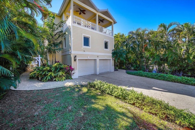 view of front of house featuring a garage, a balcony, ceiling fan, and a front lawn