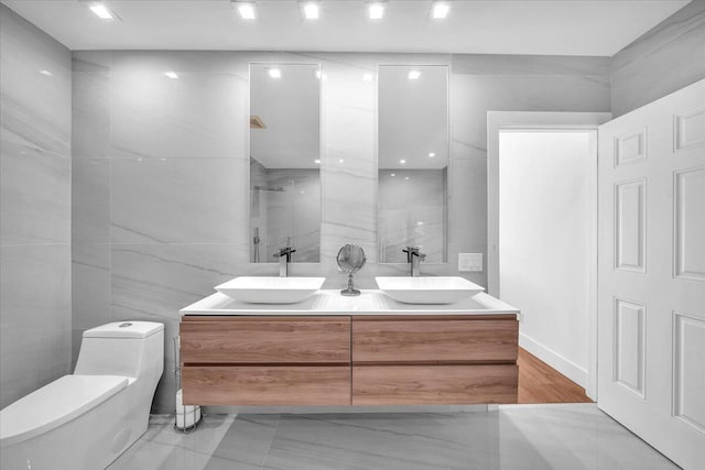 bathroom with vanity, toilet, tile walls, and a shower