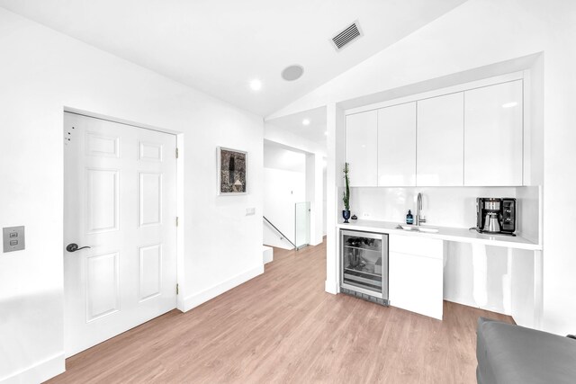 kitchen featuring white cabinetry, lofted ceiling, sink, wine cooler, and light hardwood / wood-style floors