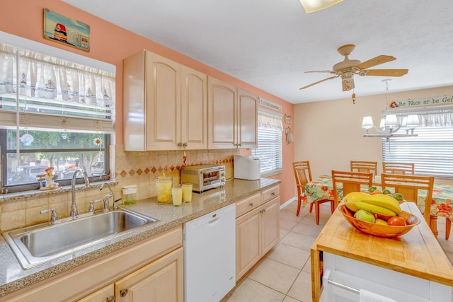 kitchen featuring tasteful backsplash, a toaster, white dishwasher, a sink, and light tile patterned flooring