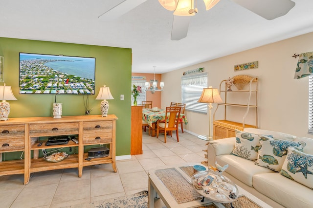 tiled living area featuring baseboards and ceiling fan with notable chandelier