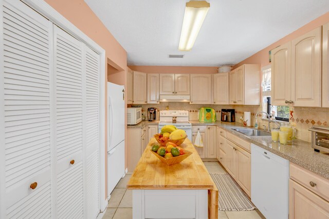 kitchen with white appliances, a sink, visible vents, wooden counters, and a center island