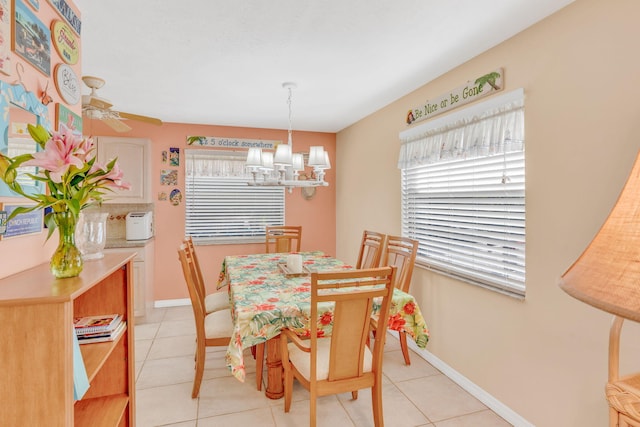 dining area featuring ceiling fan with notable chandelier, baseboards, and light tile patterned floors