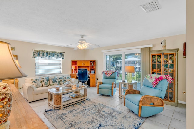 tiled living room with ceiling fan, a textured ceiling, visible vents, and a wealth of natural light