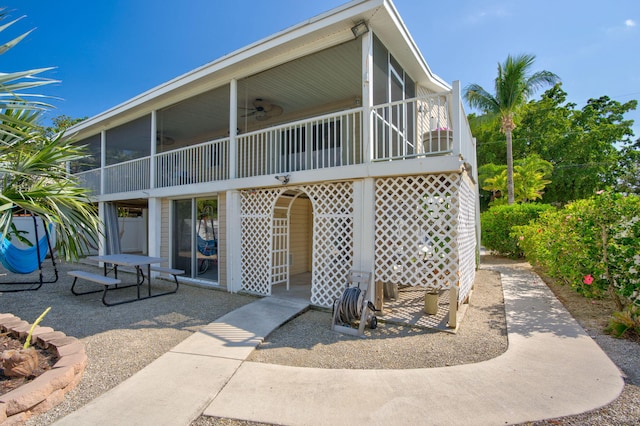 back of house featuring ceiling fan, a patio area, stairs, and a sunroom