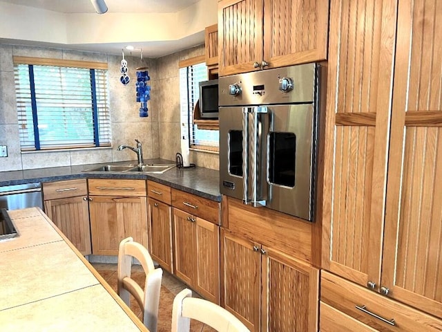 kitchen with appliances with stainless steel finishes, brown cabinets, and a sink