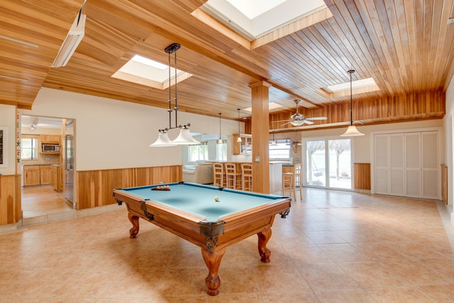 rec room with light tile patterned floors, vaulted ceiling with skylight, wooden ceiling, a ceiling fan, and wainscoting