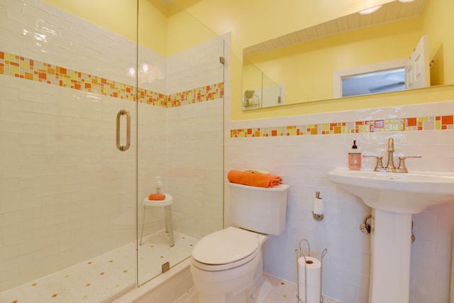 full bathroom featuring a stall shower, a sink, tile walls, and toilet