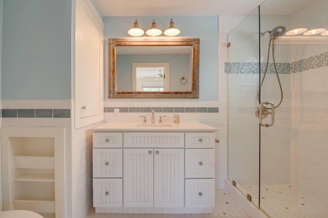 bathroom featuring an enclosed shower, vanity, built in shelves, and tile walls