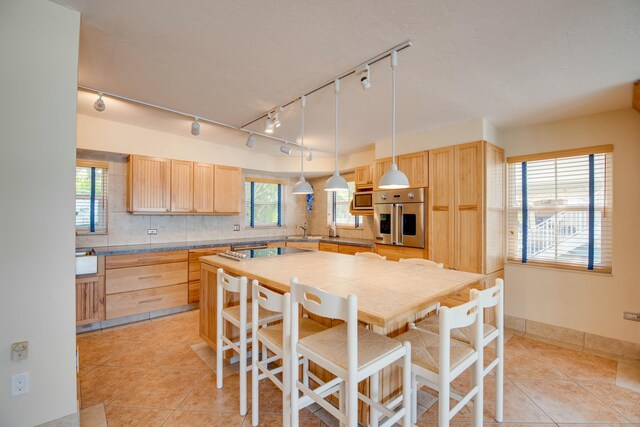 living room featuring a wood stove, light tile patterned floors, track lighting, and ceiling fan