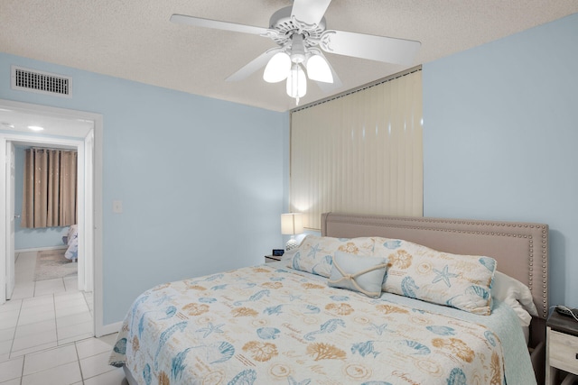 bedroom with light tile patterned floors, a ceiling fan, visible vents, and a textured ceiling