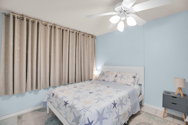 tiled bedroom with a textured ceiling, baseboards, and a ceiling fan