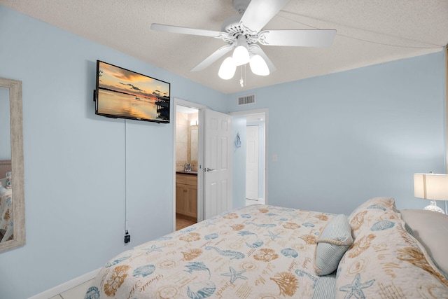 bedroom with ceiling fan, visible vents, ensuite bathroom, and a textured ceiling
