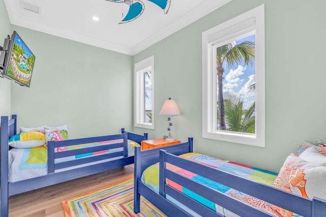 bedroom featuring multiple windows, hardwood / wood-style floors, and ornamental molding