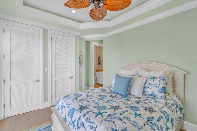 bedroom featuring crown molding, a tray ceiling, wood-type flooring, and ceiling fan