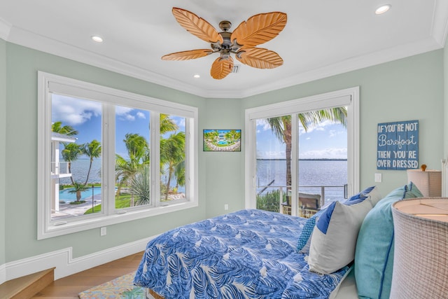 bedroom with crown molding, wood-type flooring, and a water view