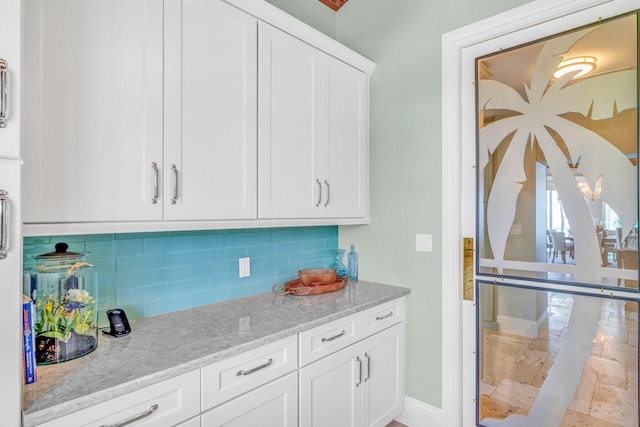 kitchen with white cabinetry, light stone countertops, and tasteful backsplash