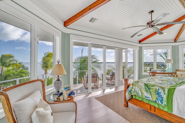 bedroom featuring hardwood / wood-style floors, beam ceiling, access to outside, and a water view