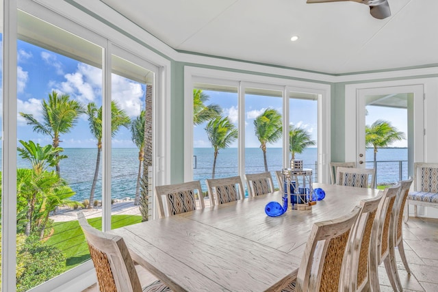 sunroom featuring ceiling fan and a water view